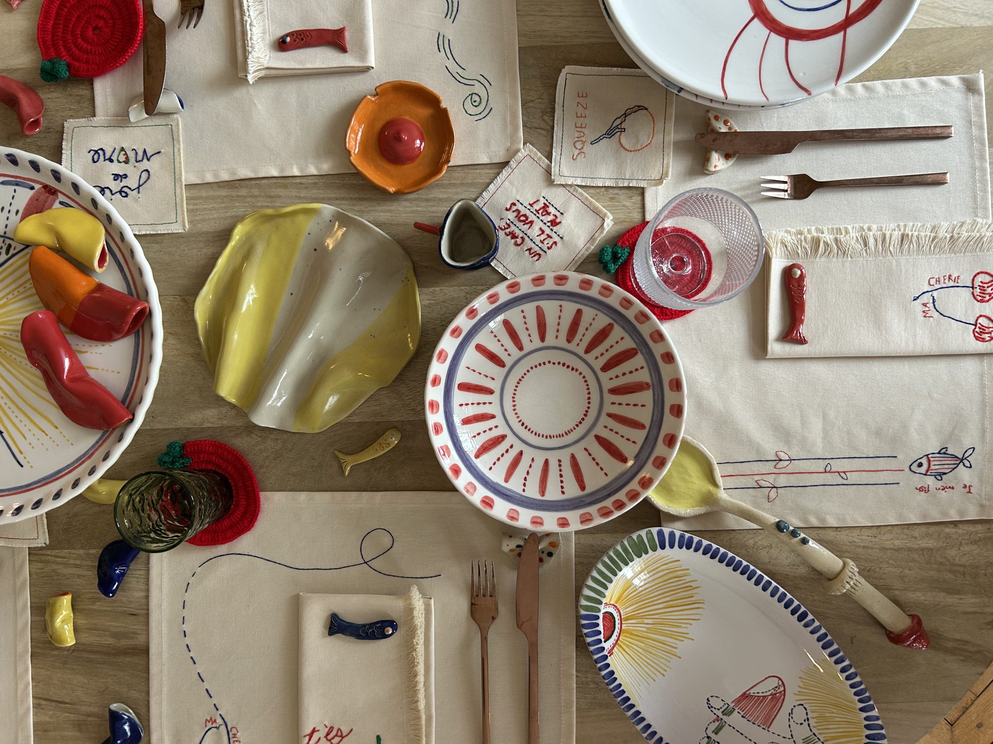 Overhead view of a table set with ceramics and embroidered linens